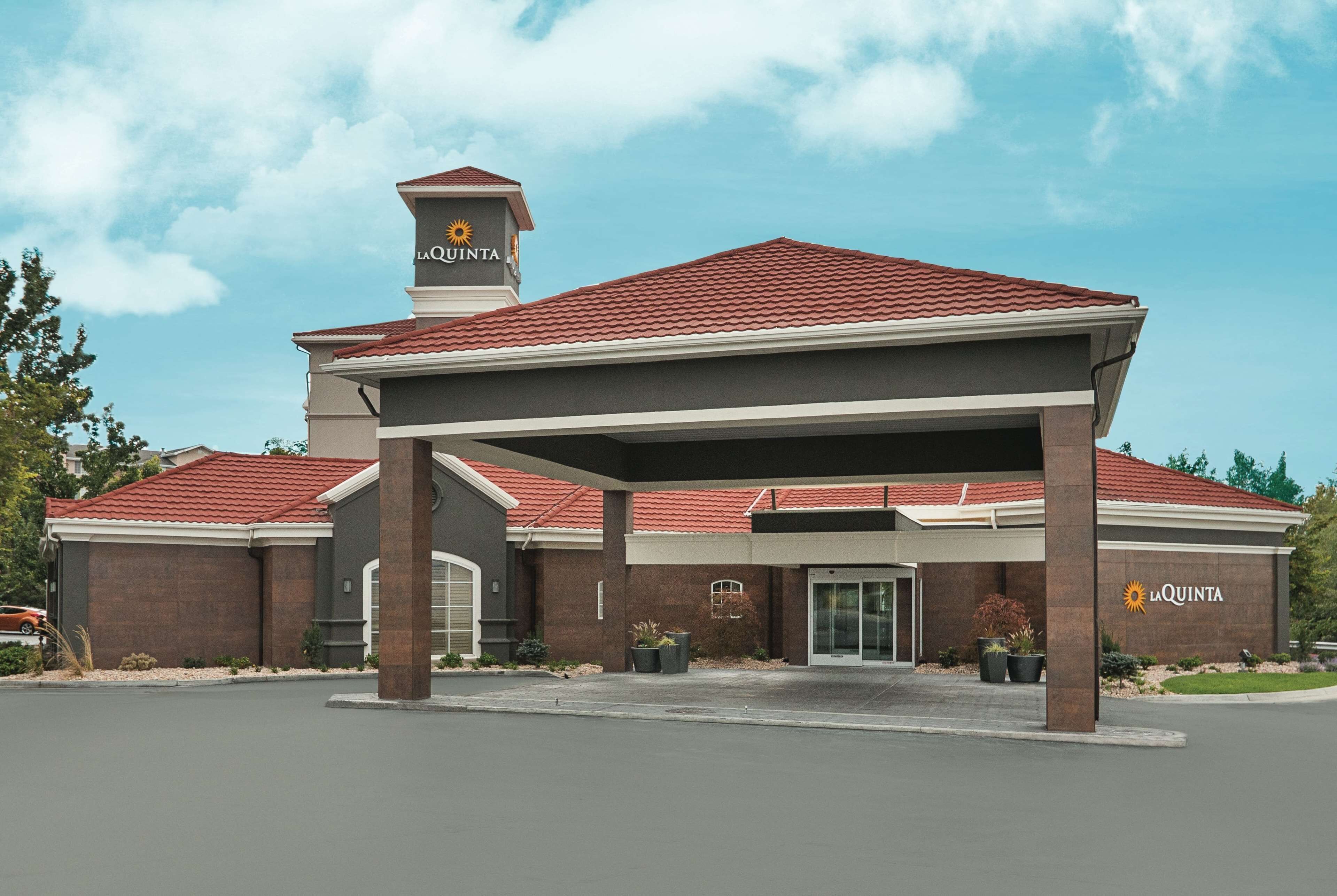 A La Quinta hotel with a red-tiled roof, a covered entrance, and a prominent tower with the hotel’s logo.