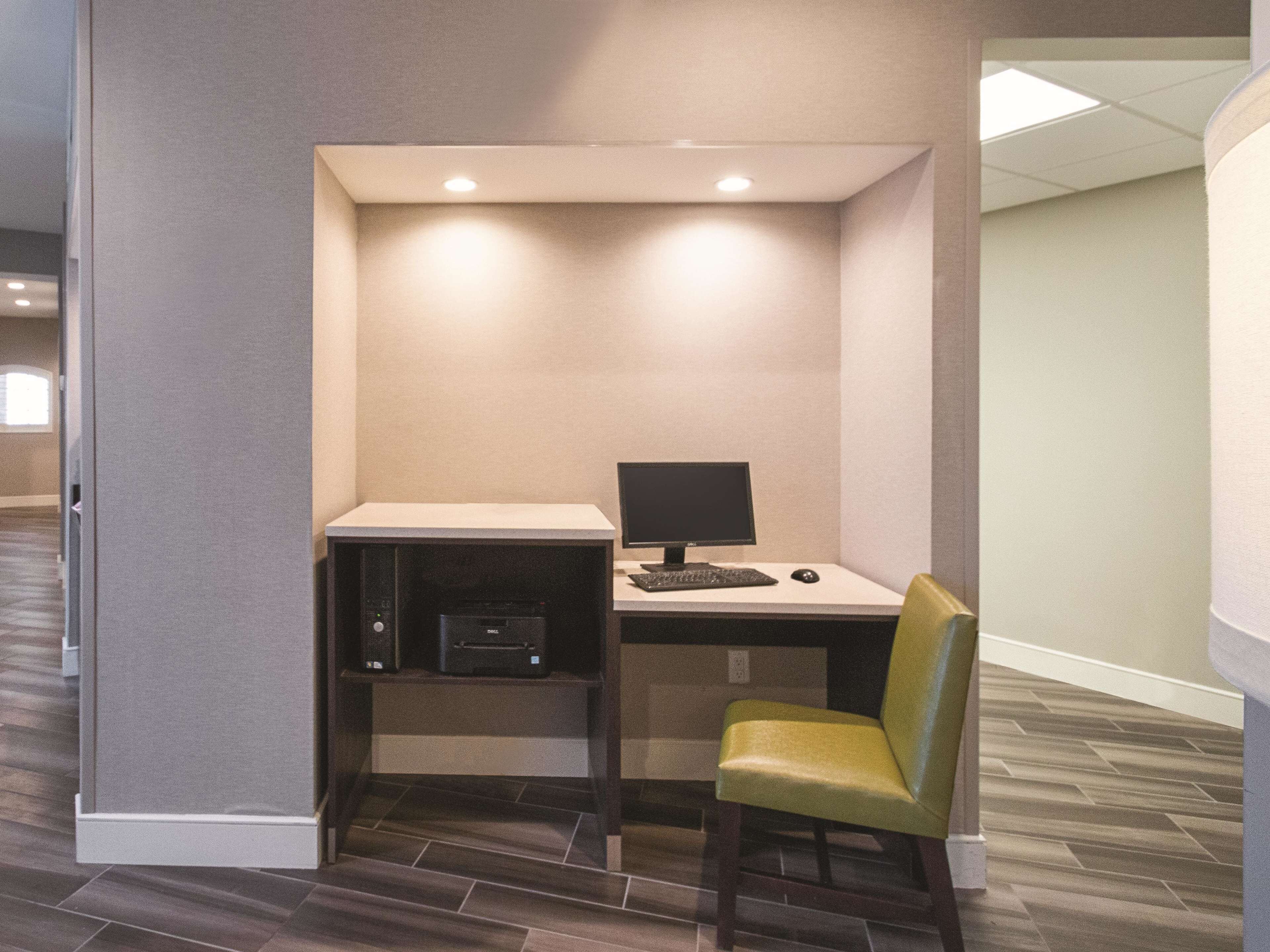 A small office space with a desk, computer, printer, and a green chair.
