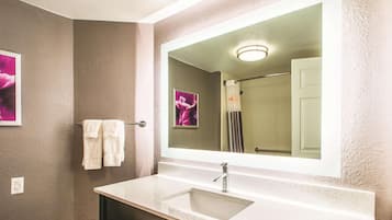 A bathroom with a large mirror, a sink, and a towel rack.