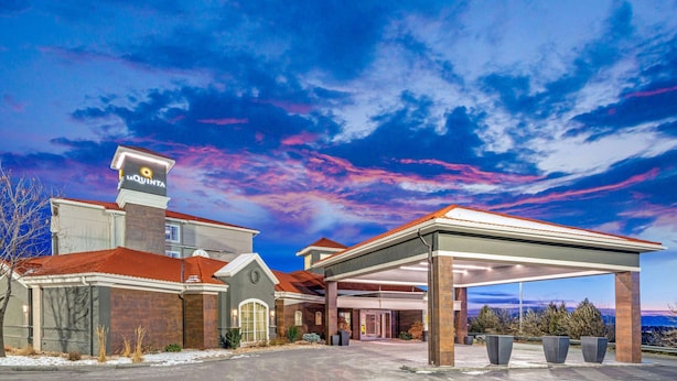 A hotel with a covered parking area, a prominent sign, and a view of the sky.