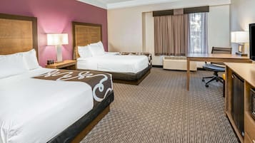 Une chambre d’hôtel avec deux lits, un bureau, une chaise, une télévision et une fenêtre avec des rideaux.