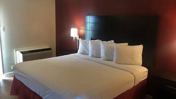 Habitación de hotel con una cama grande, una mesita de noche, una lámpara y un calentador instalado en la pared.