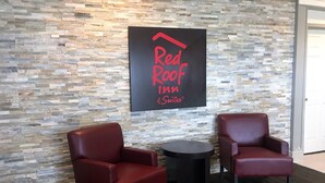 Señal de Red Roof Inn sobre una pared de piedra, dos sillones de cuero y una pequeña mesa redonda.