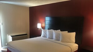 Habitación de hotel con una cama grande, una mesita de noche y una lámpara de pared, además de un radiador.
