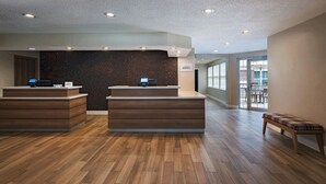 Et receptionsområde med to receptionister, en mørk væg og en bænk.