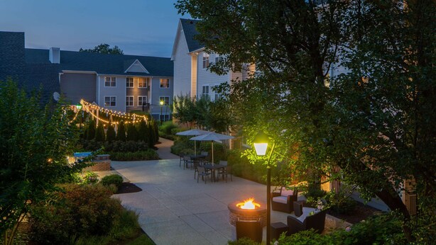 A courtyard with a fire pit, outdoor seating, and string lights. - Sonesta ES Suites Fairfax Fair Lakes (Fairfax)