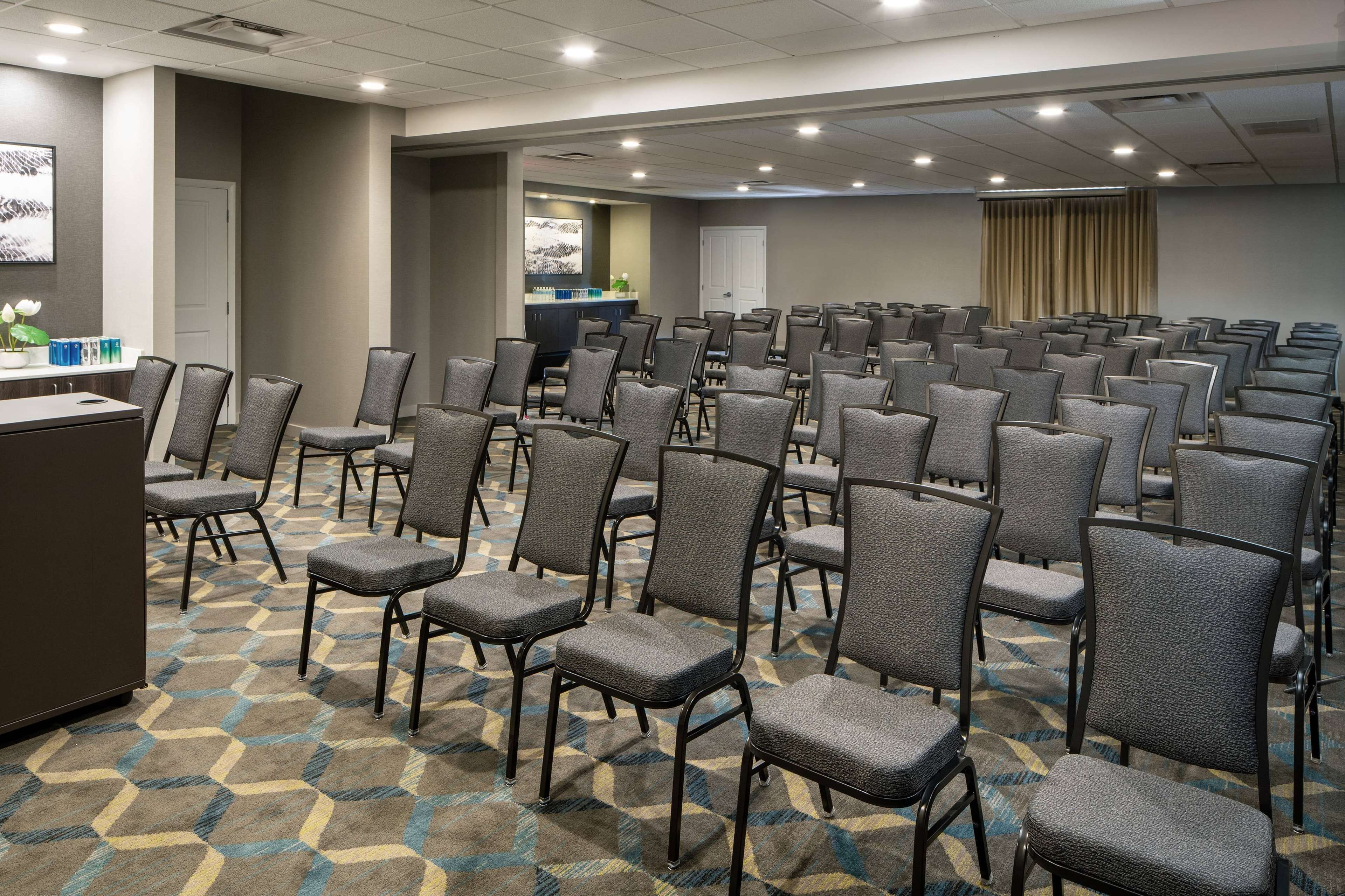 Una sala conferenze con file di sedie, un podio e un pavimento con moquette.