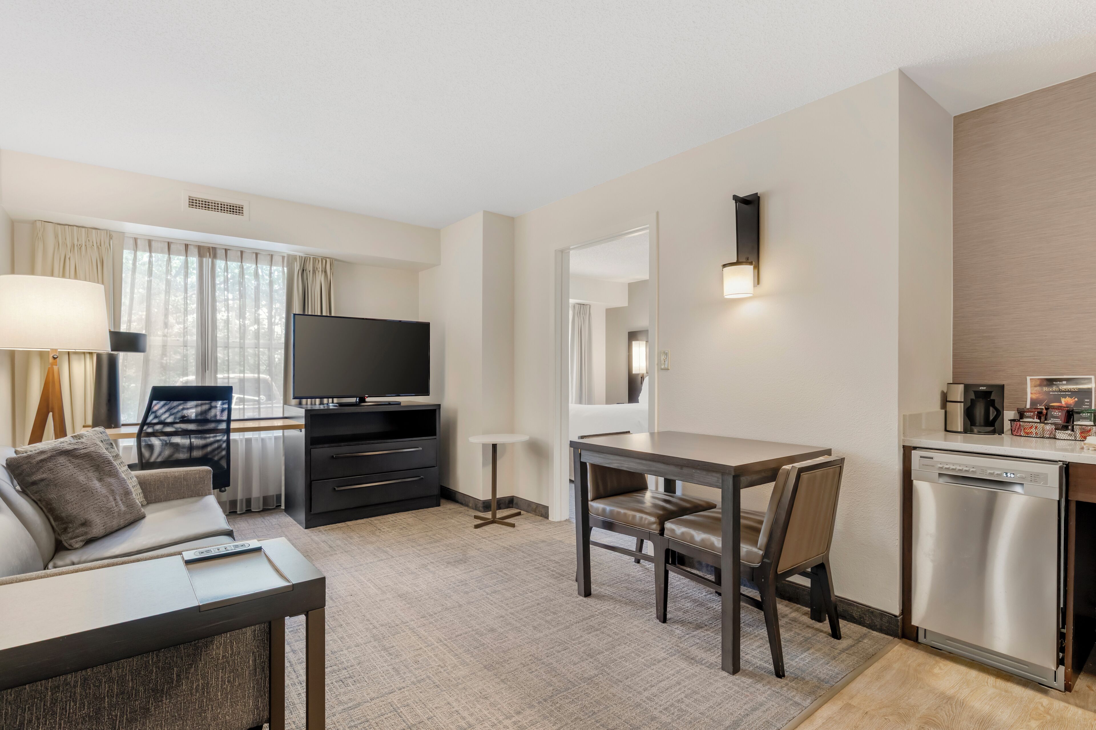 Une chambre d’hôtel moderne équipée d’un canapé, d’une télévision, d’une table à manger et d’un coin cuisine.