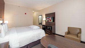 Une chambre d’hôtel équipée d’un lit, d’un bureau, d’une chaise, d’une télévision et d’un four à micro-ondes.