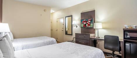 Habitación de hotel con dos camas, un escritorio, una silla, un televisor y un minibar.