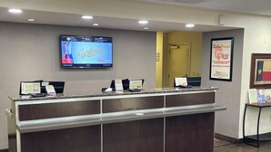 A reception desk with a digital screen displaying a welcome message, a parking sign, and a framed flag.