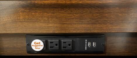 Una regleta con un cartel que dice 'Get Plugged-In', dos puertos USB y una etiqueta que indica 'DC 5V 2.1A'.