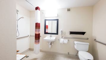 Een standaard hotelbadkamer met een douche, wastafel, toilet en een spiegel.