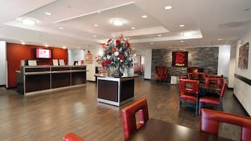 Een hotel lobby met een receptiebalie, een zithoek en een decoratieve bloemenstelling.