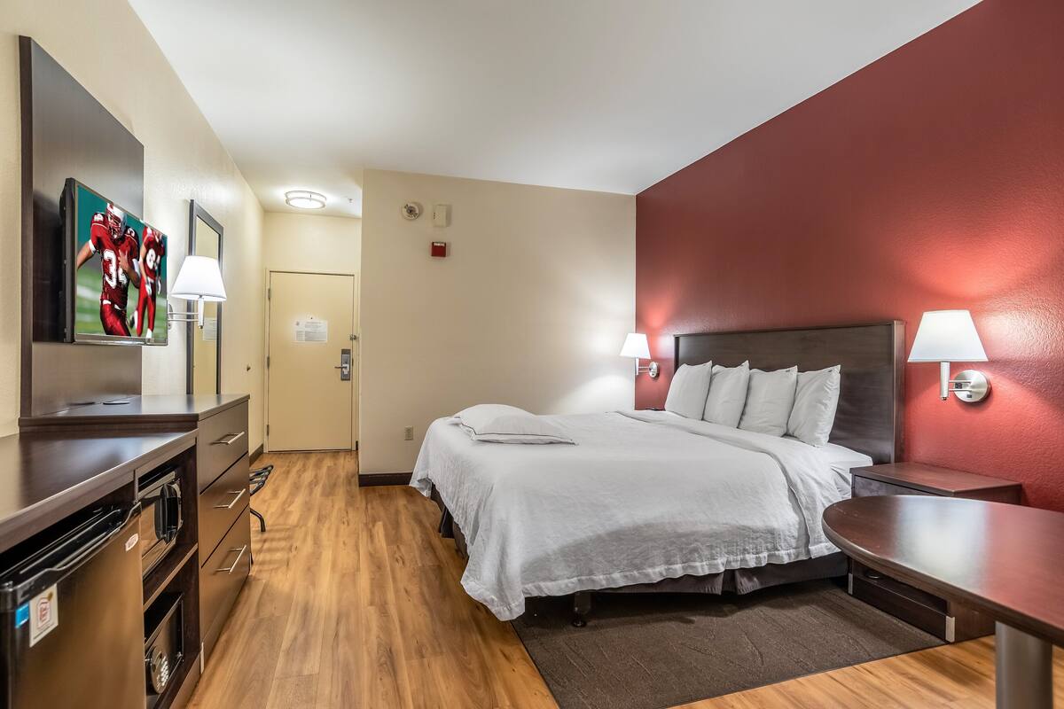 A hotel room with a bed, bedside tables, a TV, and a desk.