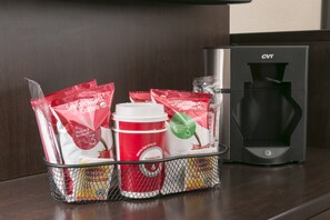 A coffee machine and a basket with coffee pods and a disposable cup. - Red Roof Inn PLUS+ San Antonio Downtown - Riverwalk (San Antonio)