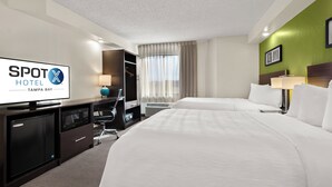 Una habitación de hotel con cama, escritorio, televisión, armario y baño.