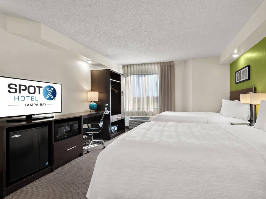 Una habitación de hotel con cama, escritorio, televisión, armario y baño.