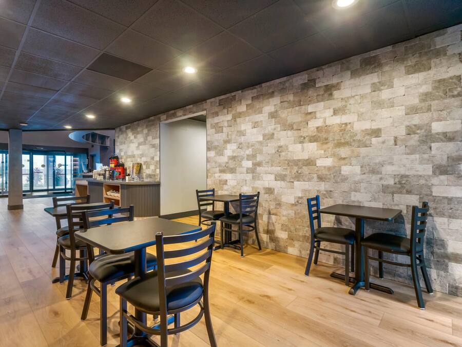A modern interior with a stone wall, wooden flooring, and a bar area with stools.