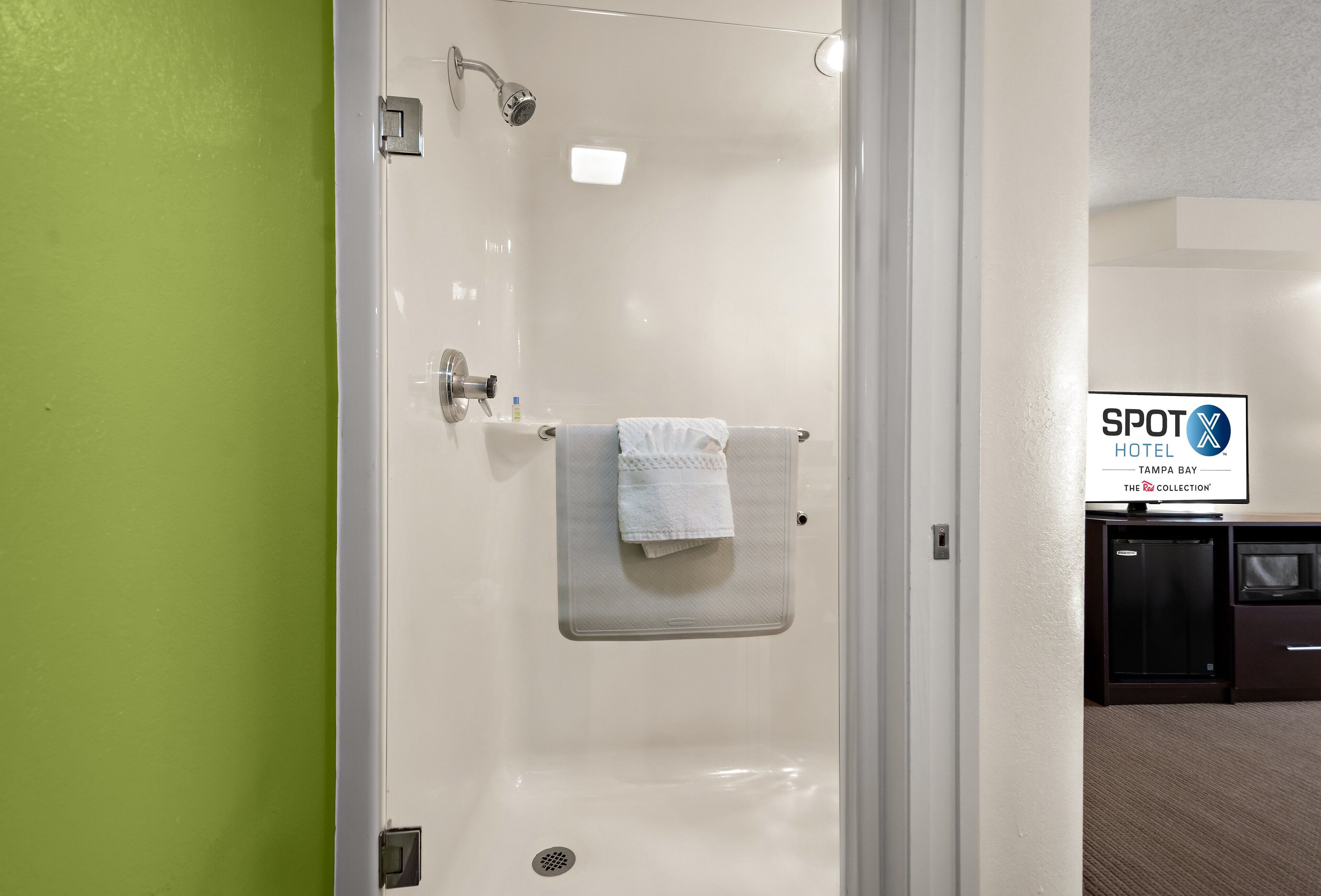 A hotel bathroom with a shower, a towel rack, and a sign indicating the hotel name.