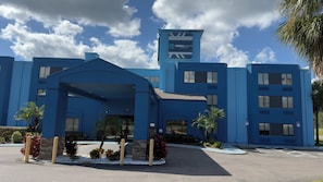 A hotel with a blue exterior, a covered entrance, and a sign indicating it is Clarion Pointe by Choice Hotels. - Clarion Pointe Wesley Chapel - Tampa Area (Wesley Chapel)