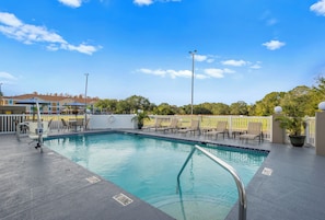 Una piscina al aire libre, sombrillas, sillones reclinables de piscina