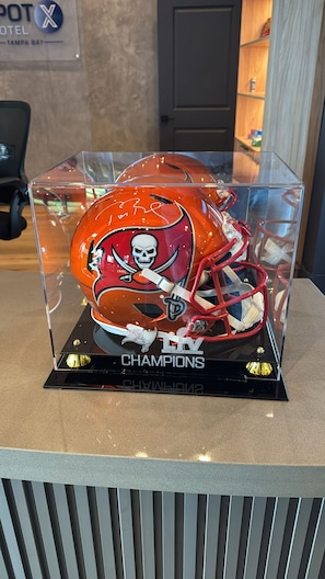 A trophy display case with a football helmet and the word "CHAMPIONS" on a black base. - SPOT X Hotel Tampa - Wesley Chapel by The Red Collection (Wesley Chapel)