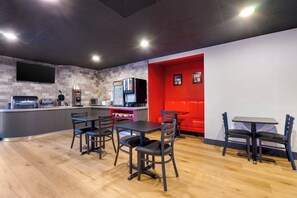 A modern restaurant interior with a counter, seating area, and a red accent wall.