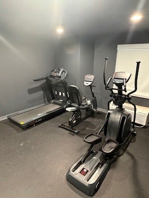 Un gimnasio con cinta de correr, elíptica y bicicleta estática.