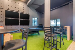 A pool table with chairs, a billiards table, and a bar area with stools. - Clarion Pointe Wesley Chapel - Tampa Area (Wesley Chapel)