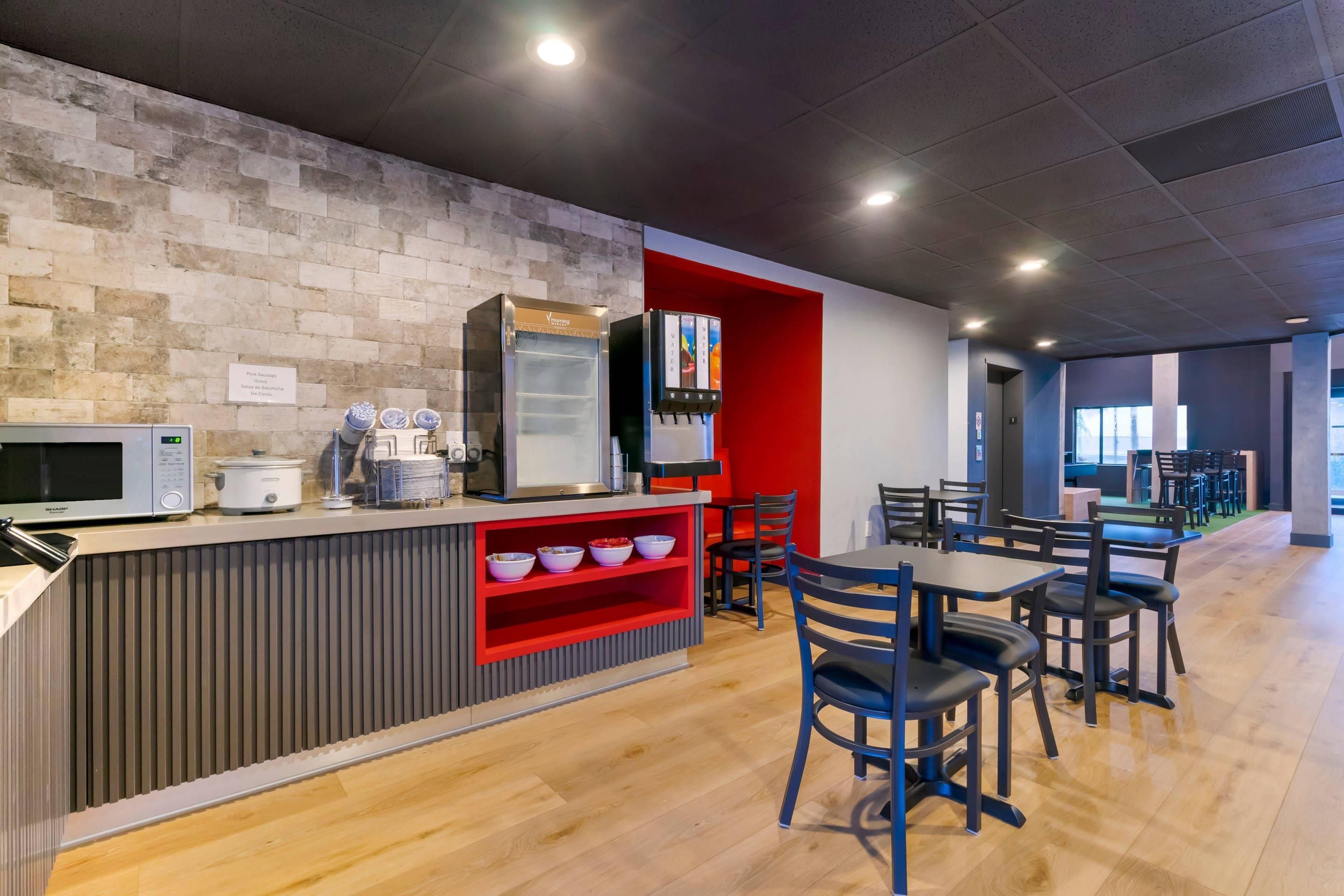 A modern cafe with a brick wall, a microwave, a coffee machine, and a water dispenser.