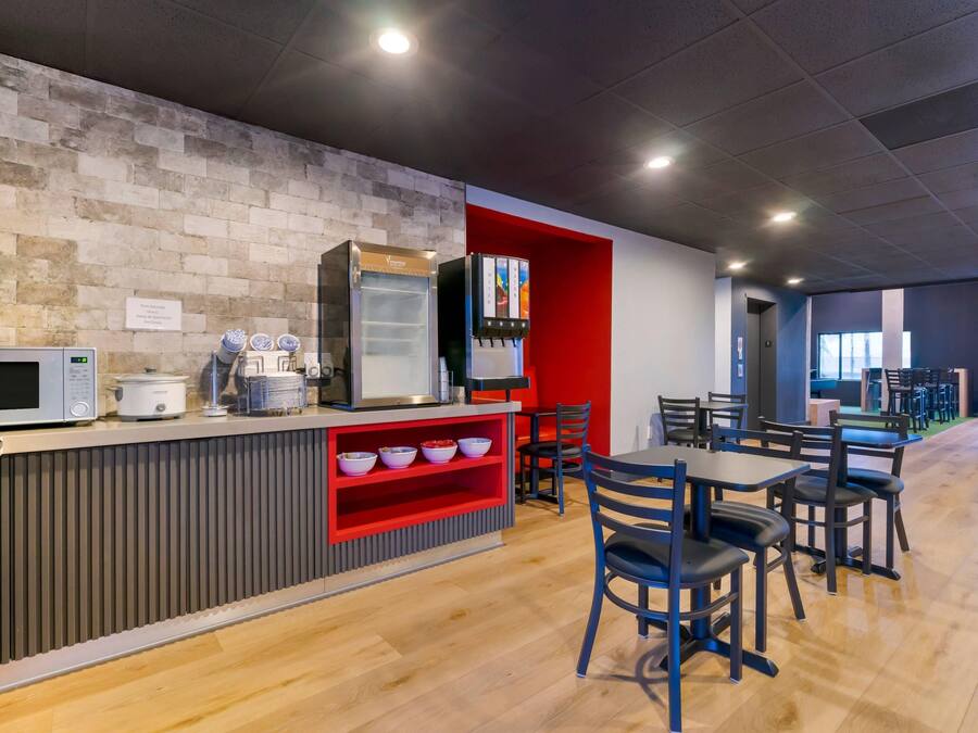 A modern cafe with a brick wall, a microwave, a coffee machine, and a water dispenser.