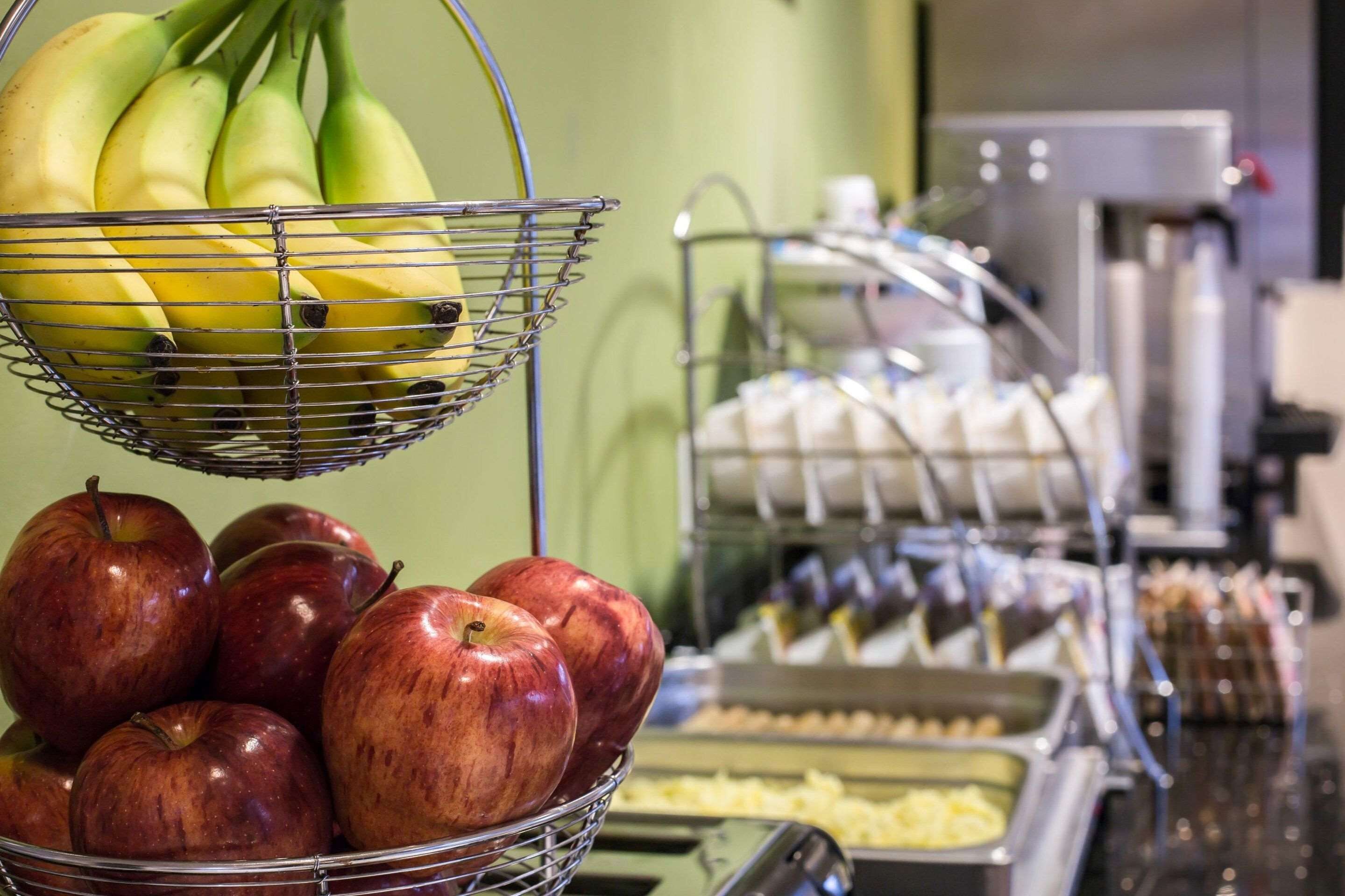 A buffet with a fruit basket containing bananas and apples.