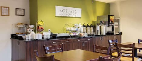 Un bar pour le petit-déjeuner avec des sièges, un réfrigérateur et une machine à café.