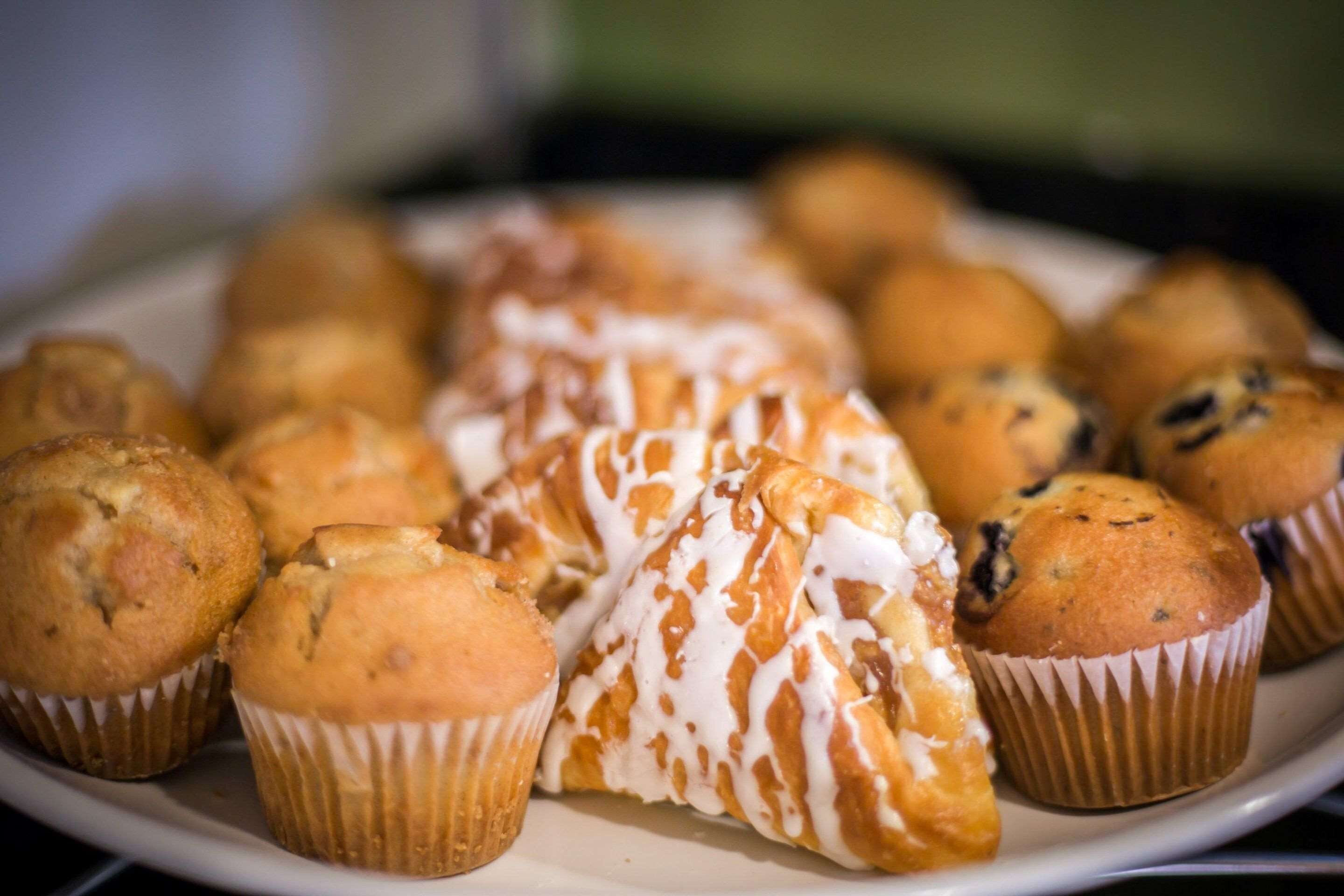 En tallrik med muffins och bakverk, inklusive en med glasyr och en med blåbär.