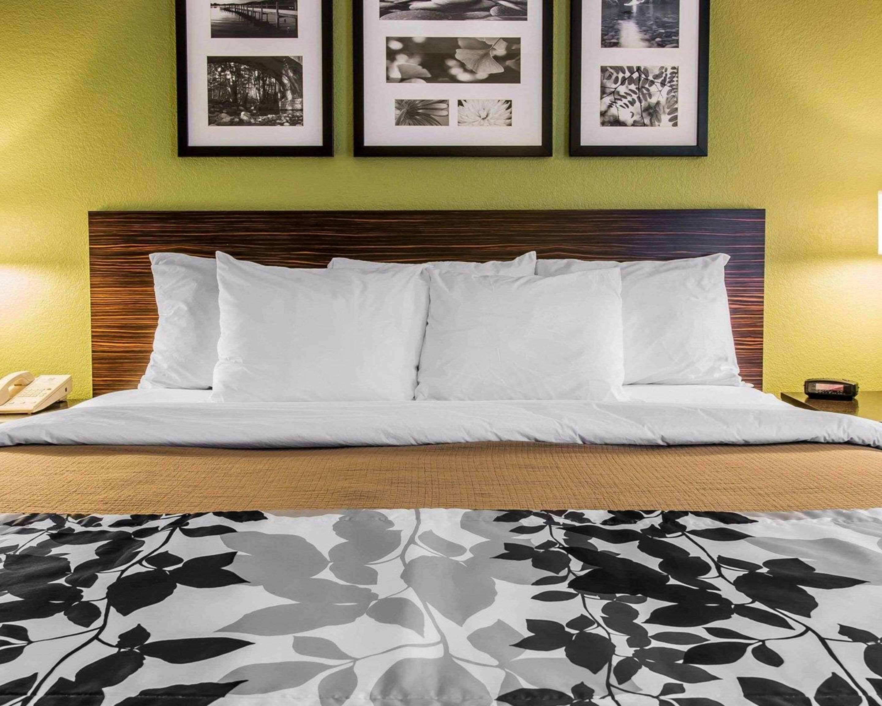 A hotel room with a bed, a wooden headboard, and three framed pictures on the wall.