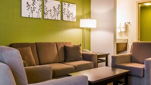 Ein Wohnzimmer mit einer Couch, Sesseln, einem Couchtisch und einer Lampe.
