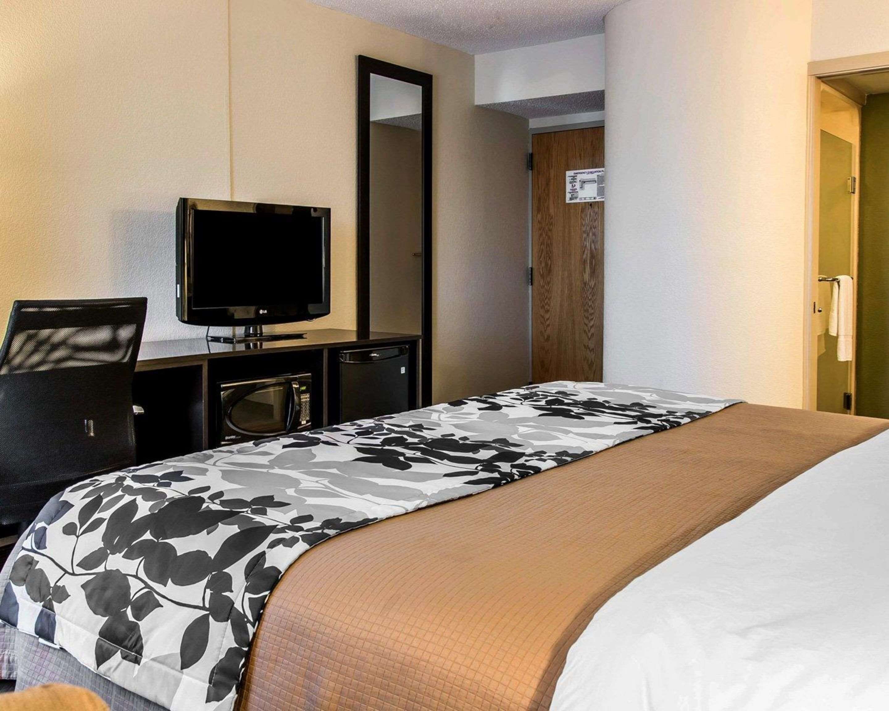 A hotel room with a bed, a television, a desk with a computer, and a microwave.