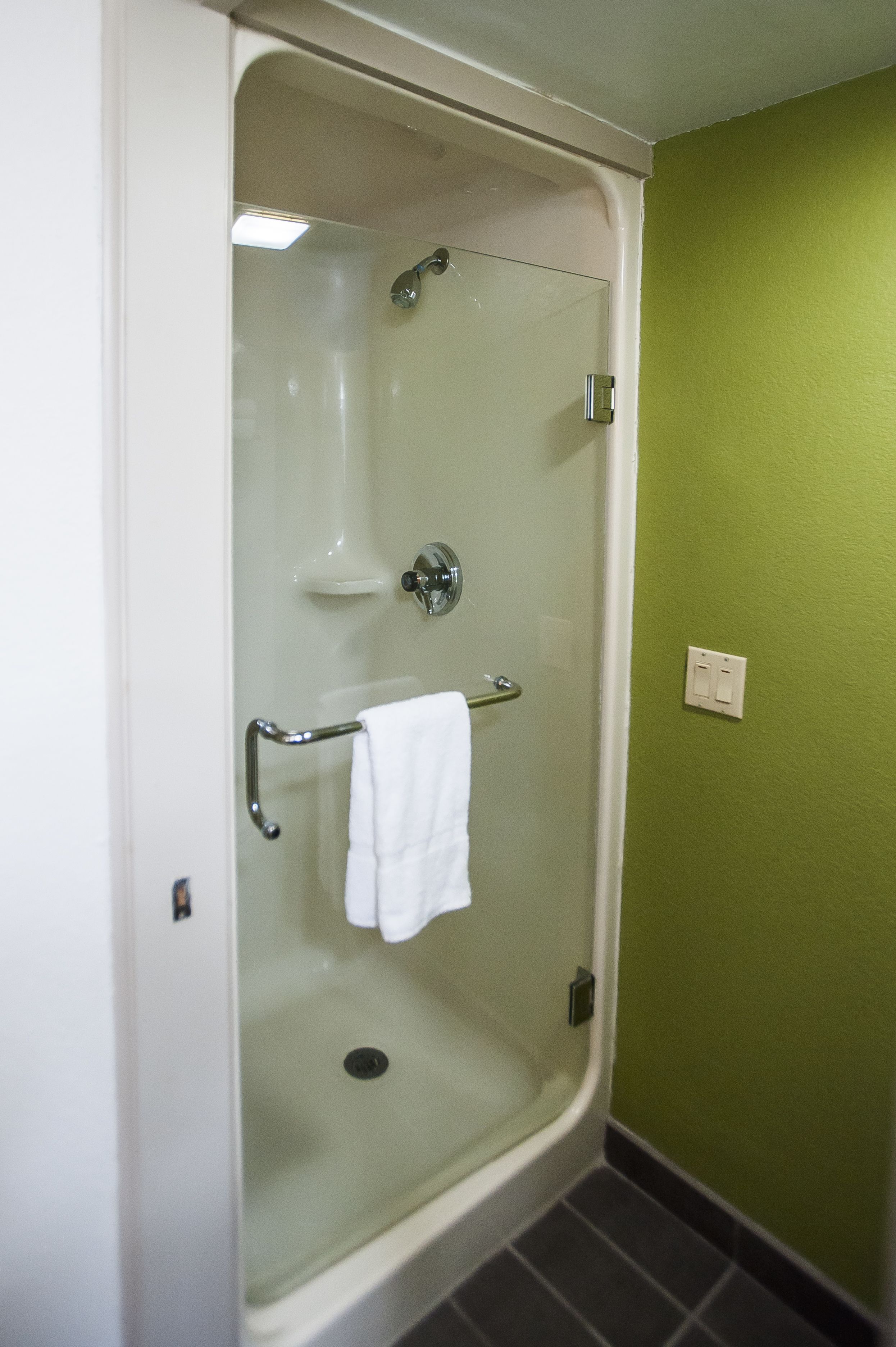A glass-enclosed shower with a white towel hanging on the door handle.