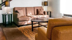 Ein modernes Wohnzimmer mit einem braunen Sofa, einem runden Couchtisch und einem gemusterten Teppich.