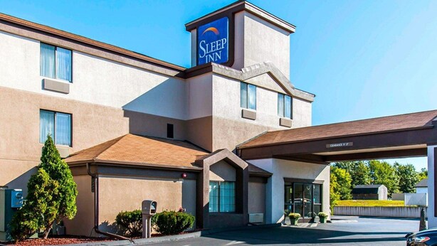 Ein Sleep Inn Hotel mit freiem Zugang, einem Parkplatz und einem überdachten Parkbereich.