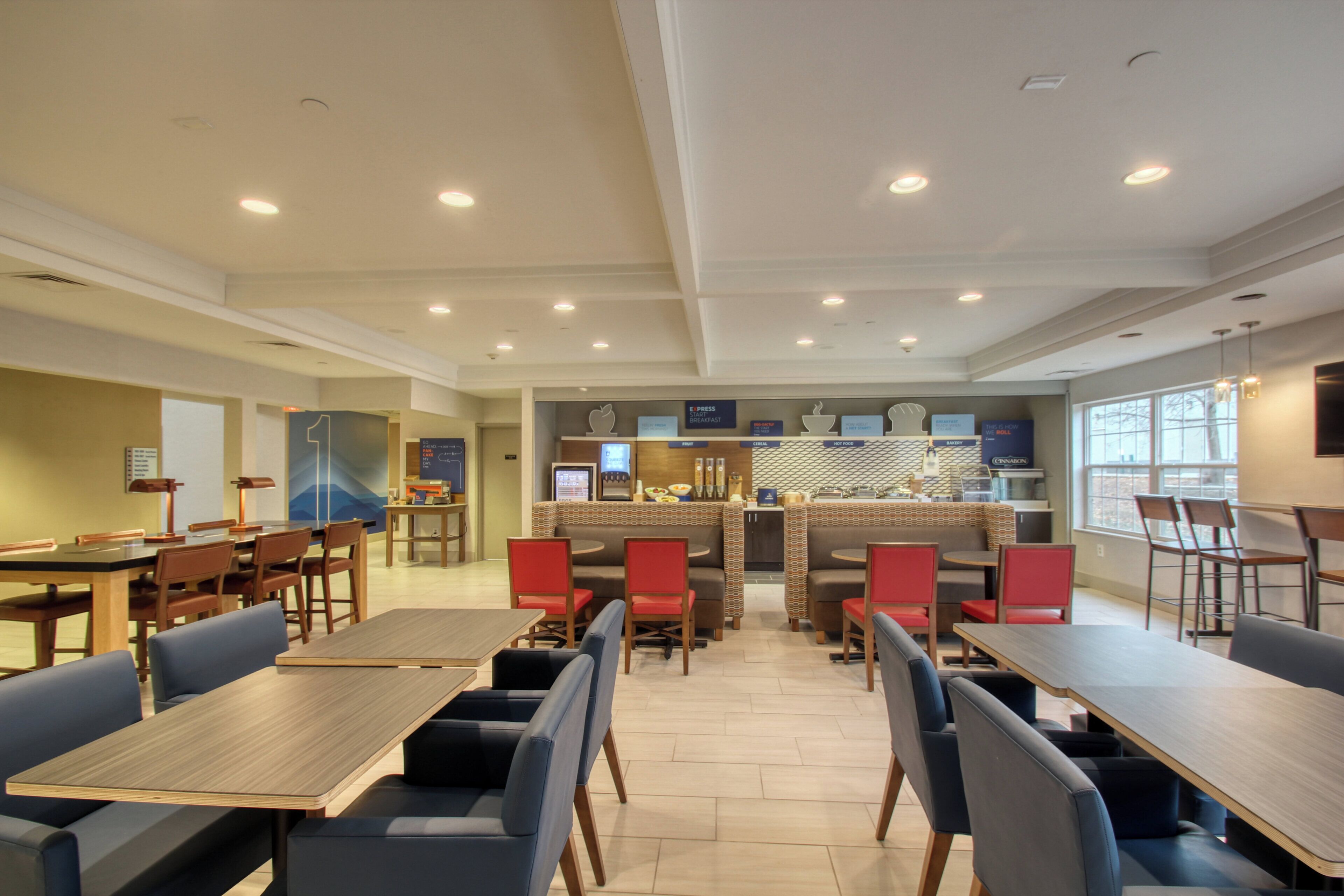 Een moderne eetruimte met verschillende zitmogelijkheden, zoals zitbankjes en tafels, en een centraal bedieningsgedeelte met diverse etalages voor de horeca.