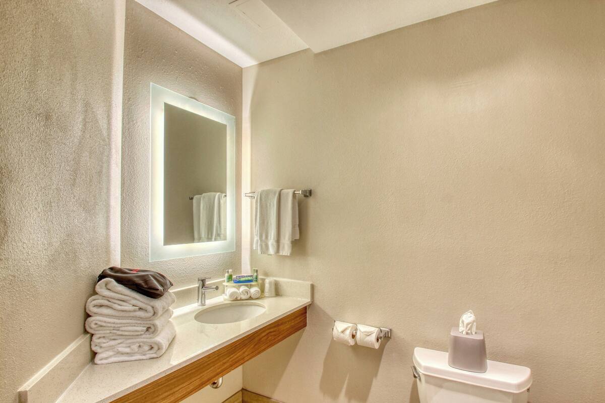 A bathroom with a sink, mirror, towel rack, and toilet.