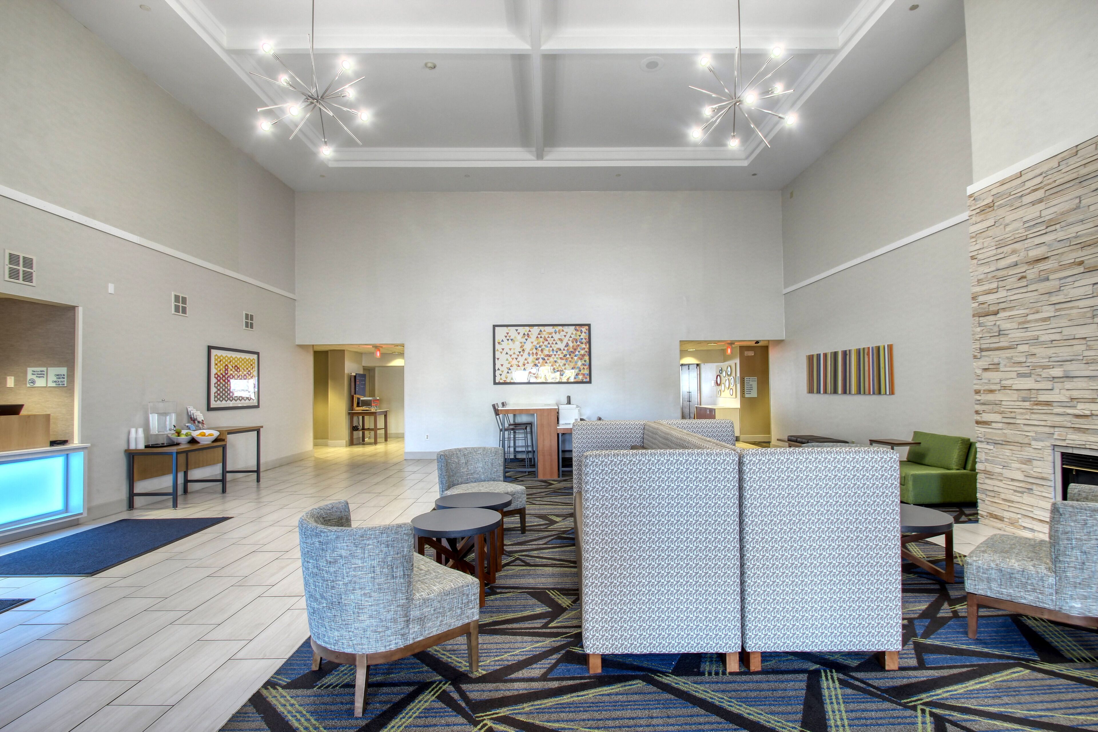 A spacious lobby with seating areas, a reception desk, and a modern chandelier.