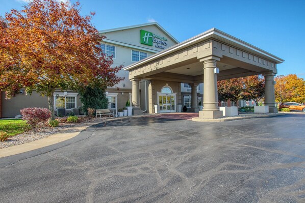 A Holiday Inn Express & Suites with a covered entrance, a parking lot, and autumn foliage. - Holiday Inn Express Hotel & Suites Oshkosh by IHG (Oshkosh)