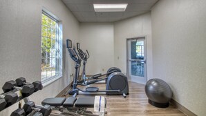 Uma academia com equipamentos de exercício, um banco, halteres e uma bola de ginástica grande.