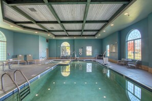 A swimming pool with a clear view of the water, a lifeguard chair, and a window with a view of trees. - Holiday Inn Express Hotel & Suites Oshkosh by IHG (Oshkosh)