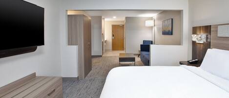 Habitación de hotel con una cama grande, un televisor de pantalla plana, un aparador de madera, un escritorio y una silla.