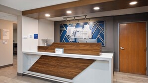A hotel reception desk with a modern design, featuring a wooden accent panel and a digital display. - Holiday Inn Express Tuscola by IHG (Tuscola)