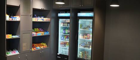 A vending area with two refrigerated beverage dispensers, a snack vending machine, and a beverage cooler.